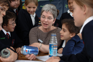 A photo of a woman teaching school children about recycling